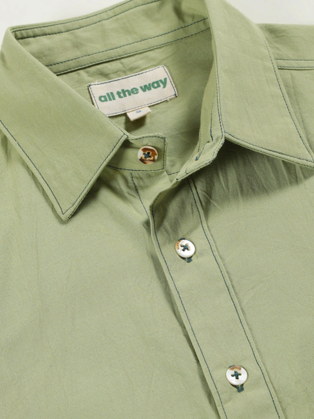 Close-up of old forest organic cotton shirt with organic cotton label printed in water-based ink, natural wooden buttons and contrast threads.