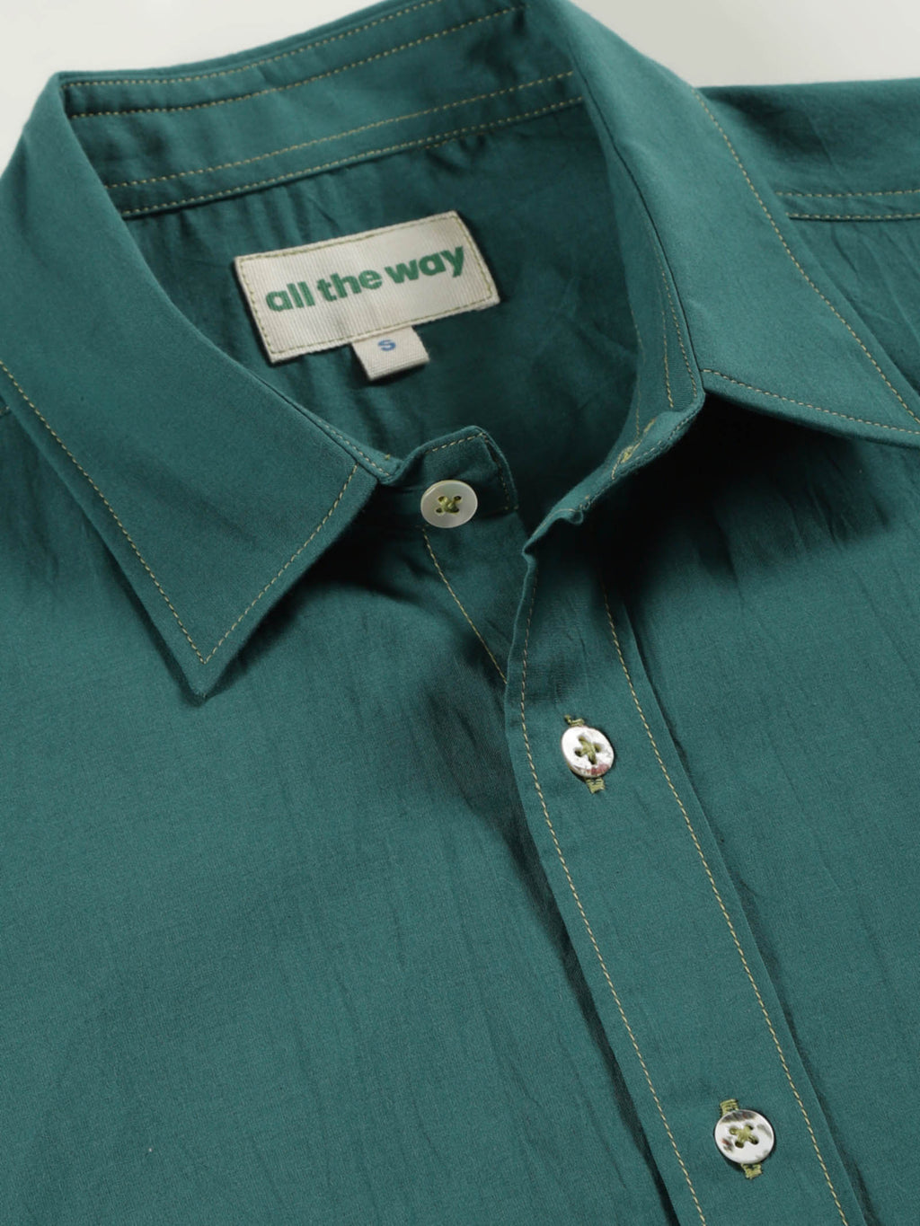 Close-up of old forest organic cotton shirt with organic cotton label printed in water-based ink, natural wooden buttons and contrast threads.