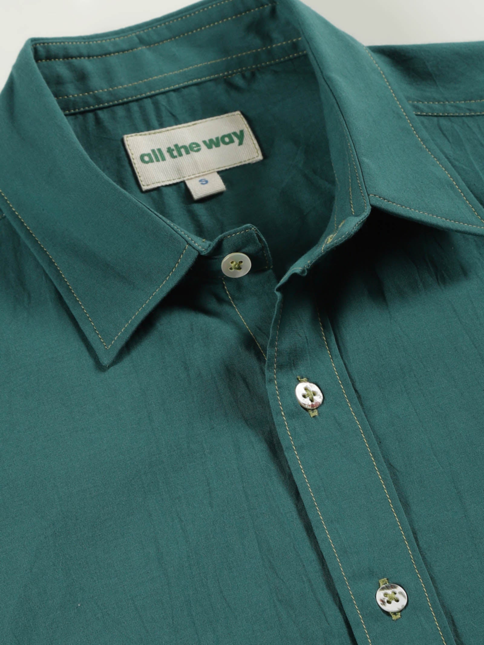 Close-up of old forest organic cotton shirt with organic cotton label printed in water-based ink, natural wooden buttons and contrast threads.