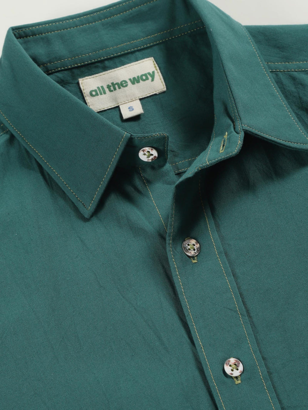 Close-up of old forest organic cotton shirt with organic cotton label printed in water-based ink, natural wooden buttons and contrast threads