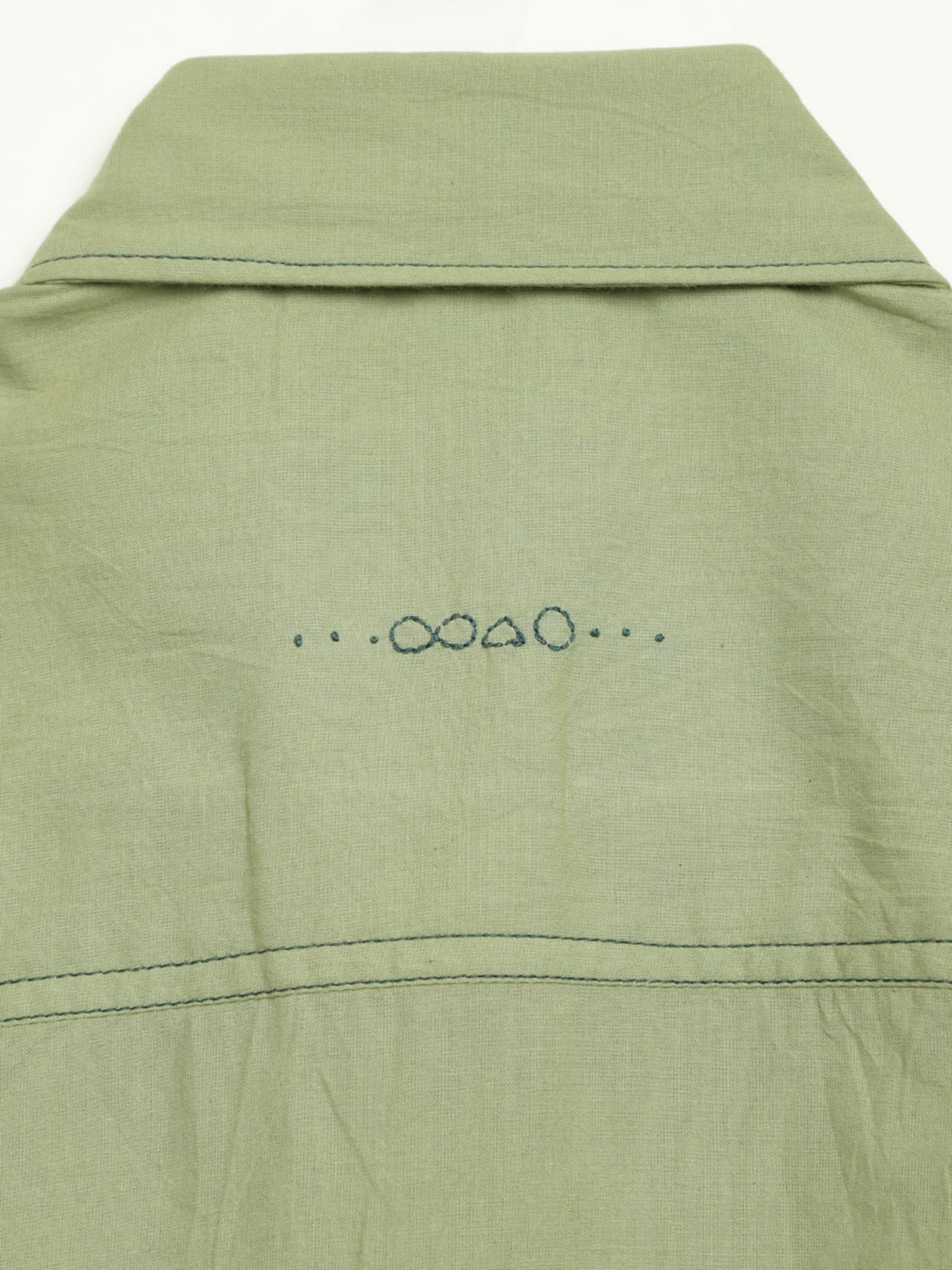 Hand-embroidered symbols on the back yoke of an organic cotton shirt — infinity, triangle and circle motifs in white thread, handcrafted by artisans in Tamil Nadu