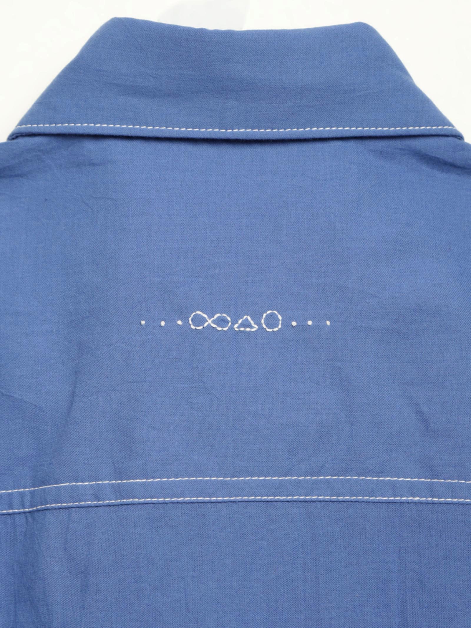Hand-embroidered symbols on the back yoke of an organic cotton shirt — infinity, triangle and circle motifs in white cotton thread, handcrafted by artisans in Tamil Nadu
