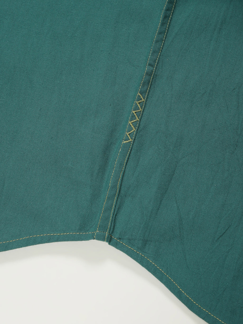 Hand-embroidered zigzag stitch at the side seam hem of a naturally dyed organic cotton shirt, handcrafted by artisans in Tamil Nadu