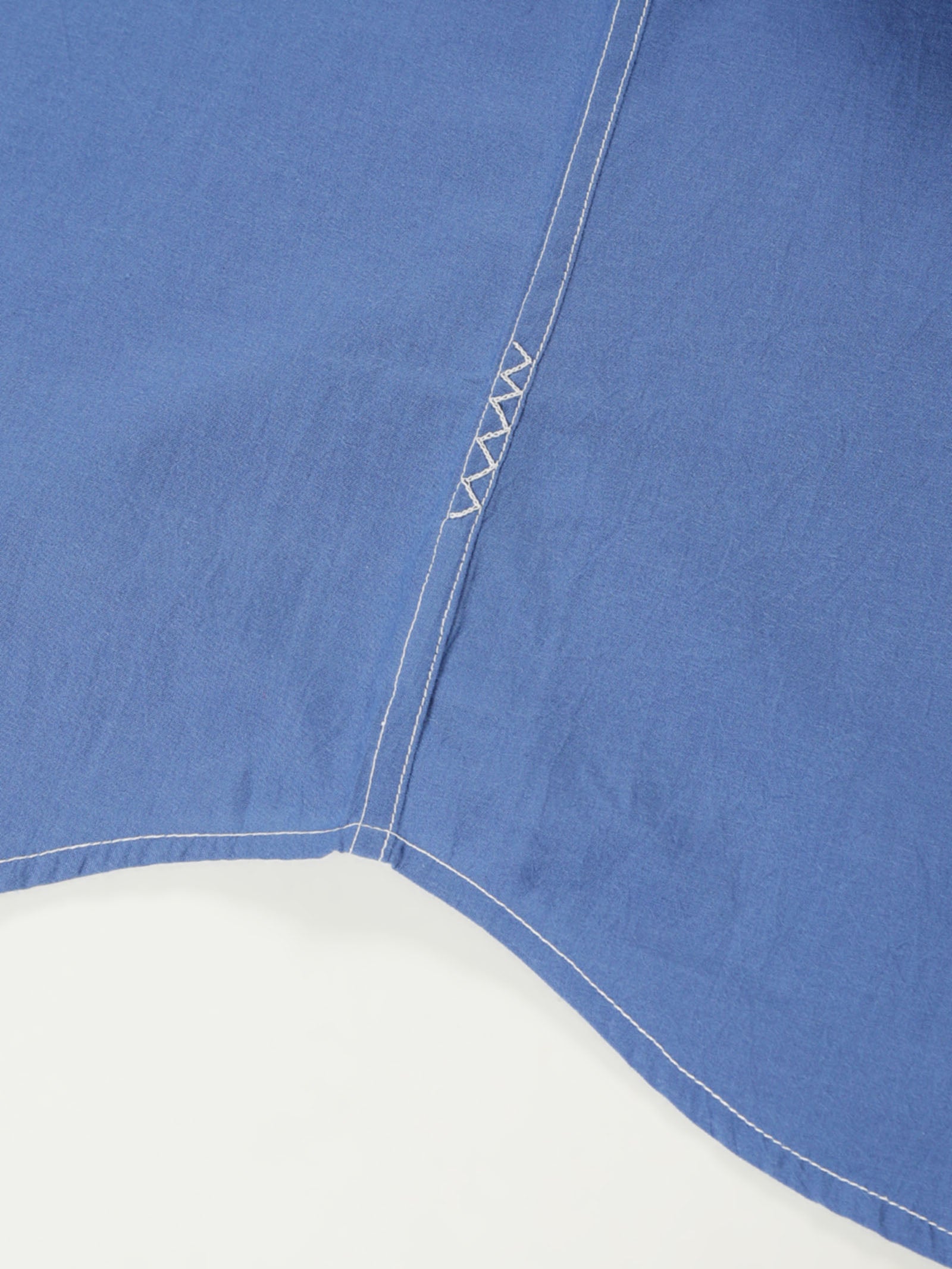Hand-embroidered zigzag stitch at the side seam hem of a naturally dyed organic cotton shirt, handcrafted by artisans in Tamil Nadu