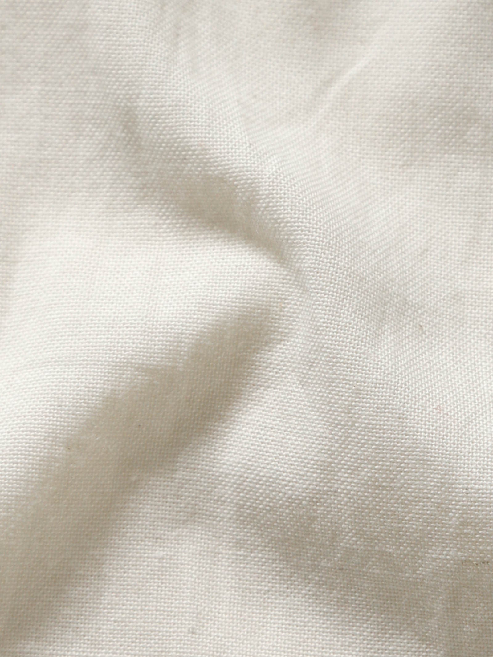 Close-up of pale olive plant-dyed organic cotton fabric showing natural texture and weave.