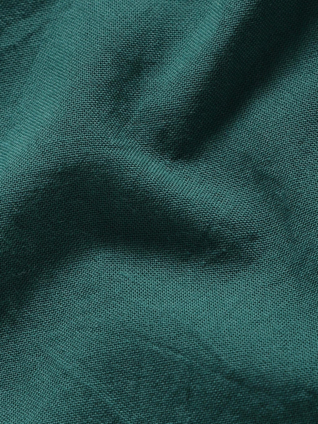 Close-up of pale olive plant-dyed organic cotton fabric showing natural texture and weave