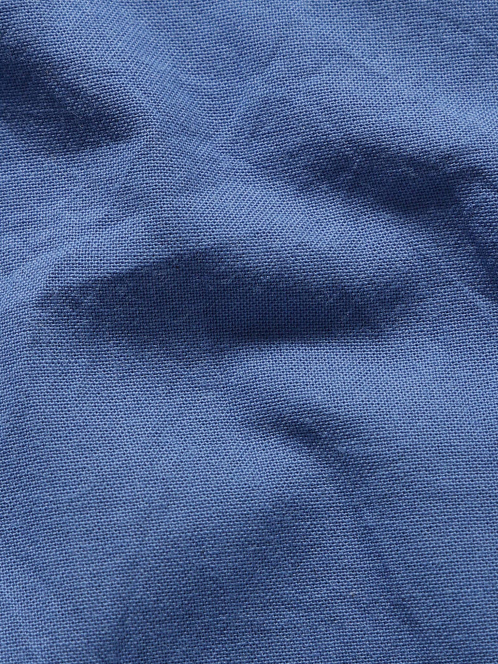 Close-up of pale olive plant-dyed organic cotton fabric showing natural texture and weave.