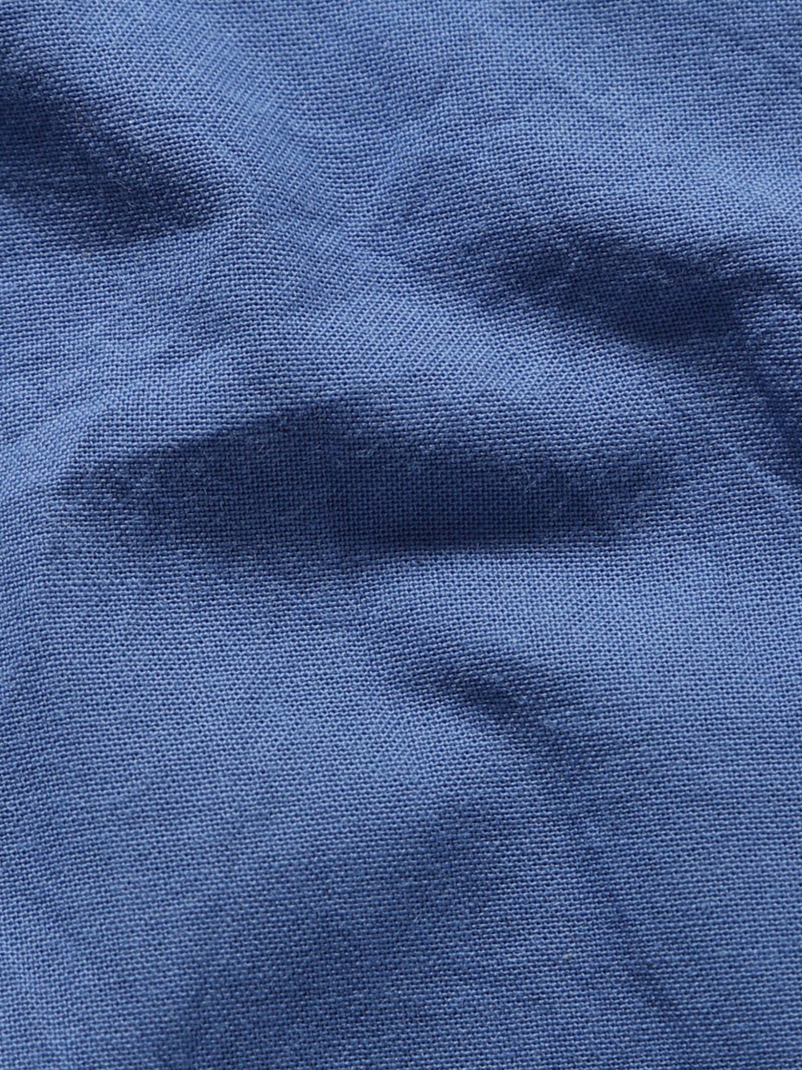 Close-up of pale olive plant-dyed organic cotton fabric showing natural texture and weave.